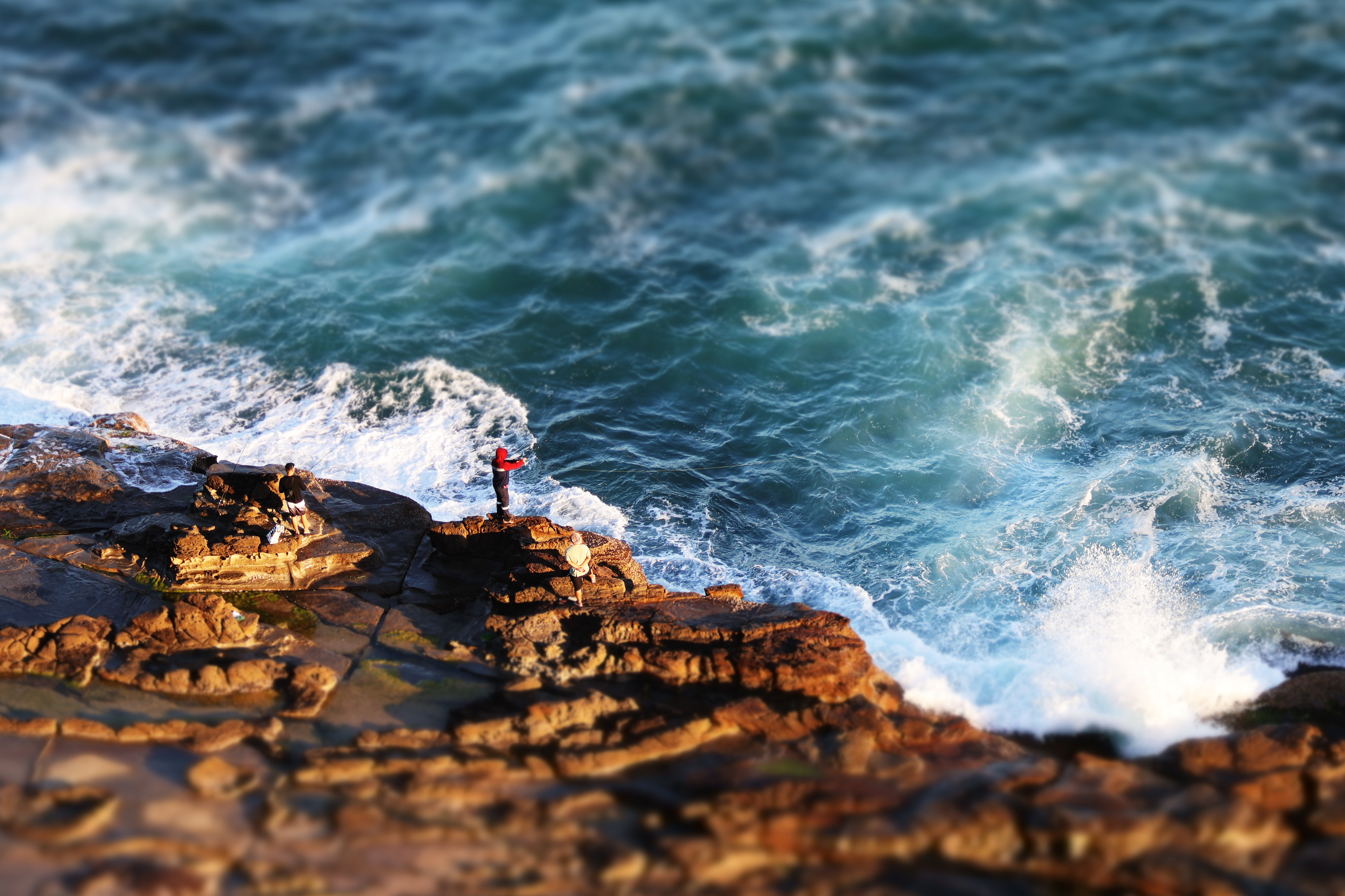 Fishermen on sandstone cliffs over ocean